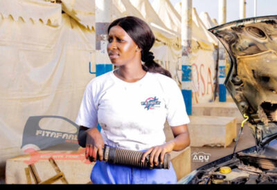 Image of Ida Faal, a female auto mechanic, working on a car in The Gambia.